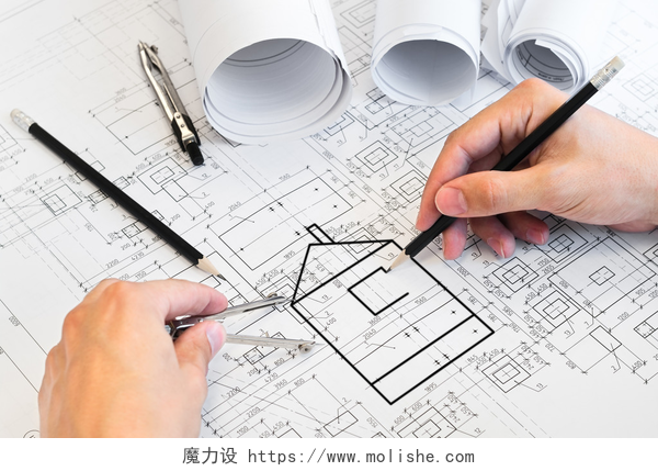 一个人手持圆规铅笔在画工程图纸绘制一个项目